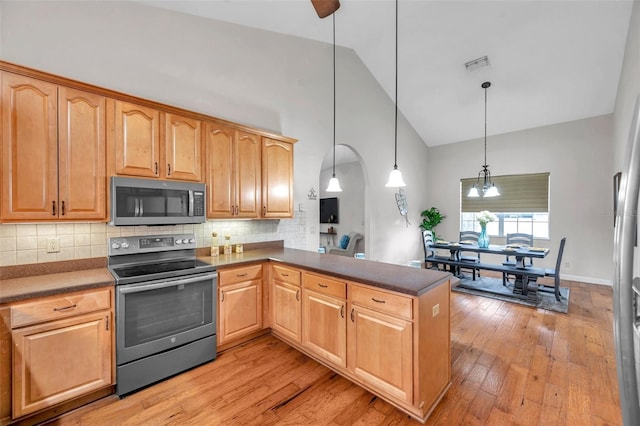 kitchen featuring hanging light fixtures, kitchen peninsula, tasteful backsplash, and stainless steel appliances