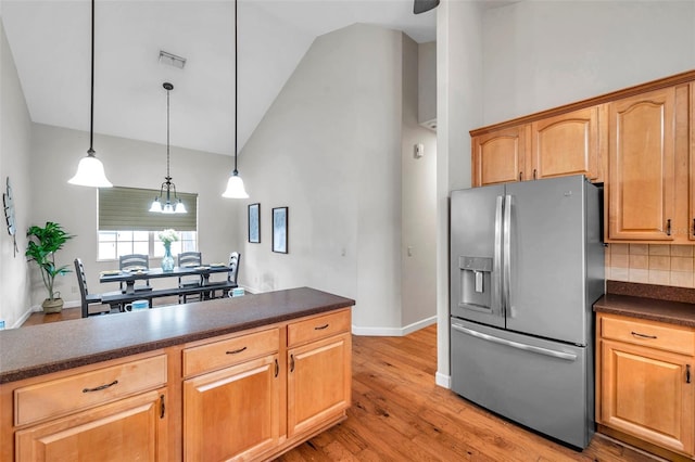 kitchen with decorative light fixtures, tasteful backsplash, stainless steel fridge, high vaulted ceiling, and light hardwood / wood-style flooring