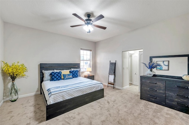 bedroom featuring ceiling fan, light colored carpet, and a textured ceiling