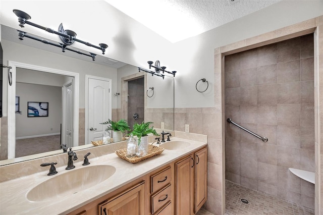 bathroom featuring a textured ceiling, tiled shower, vanity, and tile walls