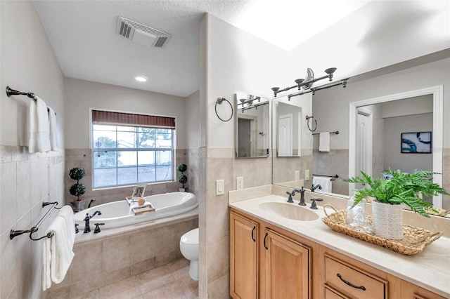 bathroom with toilet, tiled tub, tile walls, tile patterned floors, and vanity