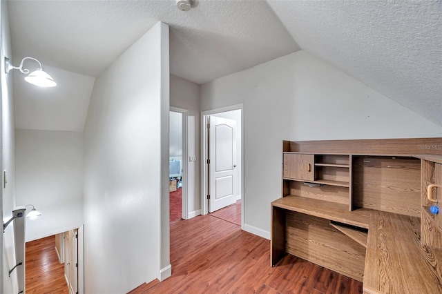 interior space featuring lofted ceiling, wood-type flooring, and a textured ceiling