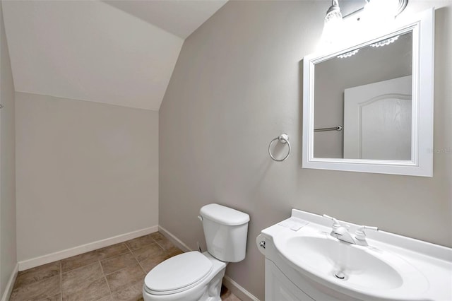 bathroom with toilet, vanity, and vaulted ceiling