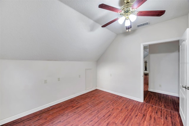 additional living space featuring vaulted ceiling, ceiling fan, dark hardwood / wood-style flooring, and a textured ceiling