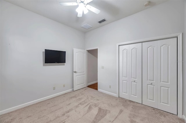 unfurnished bedroom featuring ceiling fan, light colored carpet, and a closet