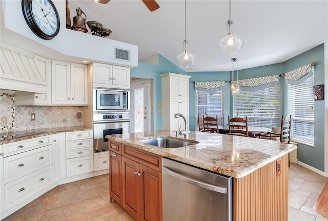 kitchen featuring white cabinetry, stainless steel appliances, tasteful backsplash, sink, and a kitchen island with sink