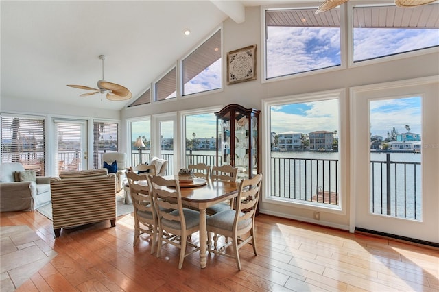 sunroom featuring a water view, lofted ceiling with beams, and ceiling fan