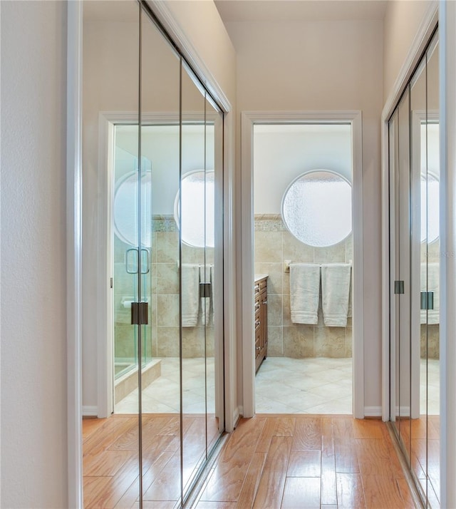 doorway to outside featuring tile walls and light wood-type flooring