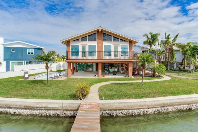 back of property featuring a fenced in pool, a lawn, a water view, and a patio