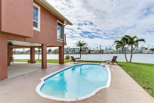 view of pool with a patio area, a lawn, and a water view