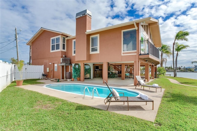 back of property featuring central AC unit, a fenced in pool, a patio area, and a lawn