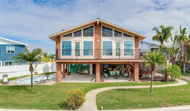 rear view of house with a lawn, a patio area, and a fenced in pool