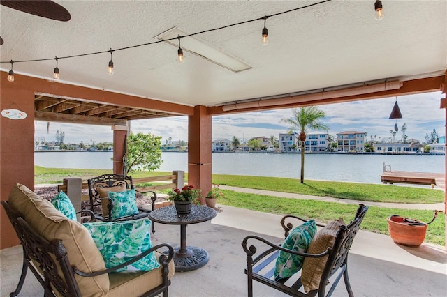 view of patio with a water view, an outdoor living space, and ceiling fan