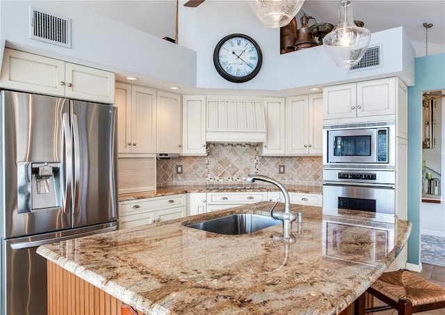 kitchen featuring white cabinetry, a kitchen island with sink, light stone countertops, sink, and appliances with stainless steel finishes