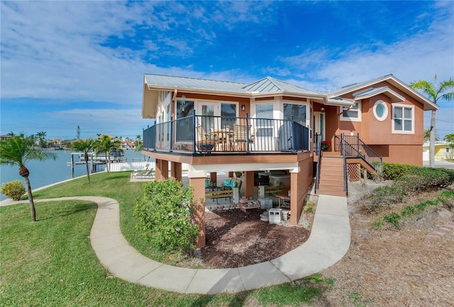 rear view of house featuring a deck with water view and a yard