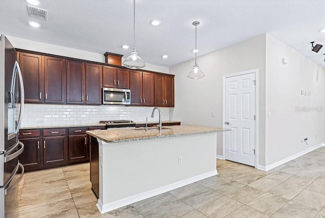 kitchen with stainless steel appliances, a center island with sink, sink, and pendant lighting