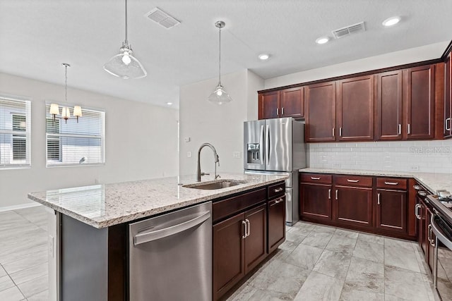 kitchen featuring appliances with stainless steel finishes, hanging light fixtures, a kitchen island with sink, and sink