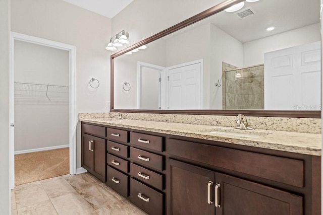 bathroom with a tile shower and vanity