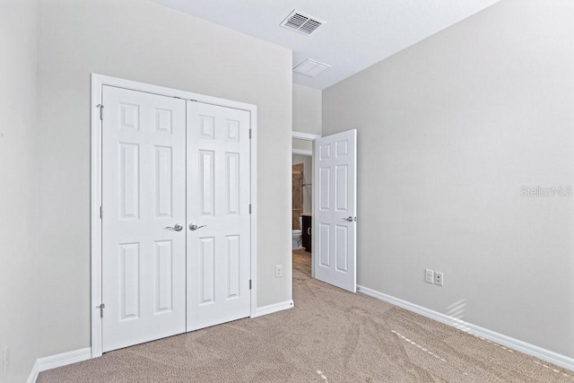 unfurnished bedroom featuring a closet and light colored carpet