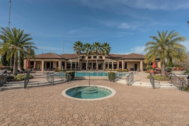 rear view of house featuring a swimming pool with hot tub and a patio area