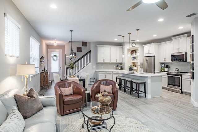 living room featuring ceiling fan, light hardwood / wood-style flooring, and sink