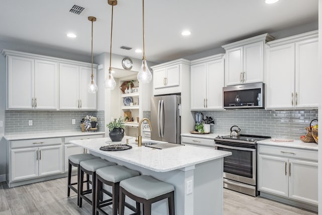 kitchen with appliances with stainless steel finishes, backsplash, pendant lighting, and white cabinetry