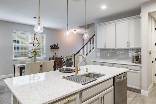 kitchen with sink, decorative light fixtures, tasteful backsplash, stainless steel dishwasher, and a center island with sink