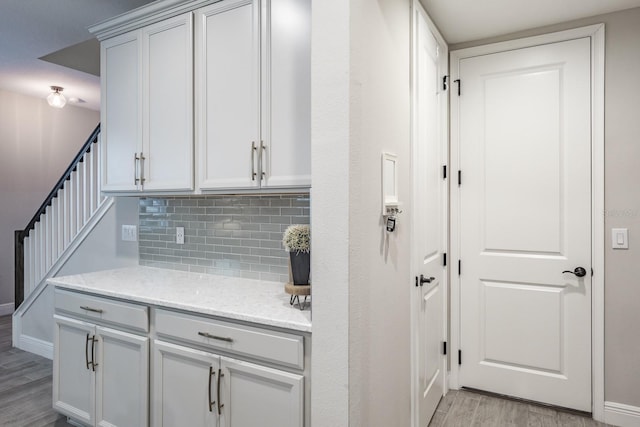 kitchen featuring light stone counters, light hardwood / wood-style floors, and tasteful backsplash