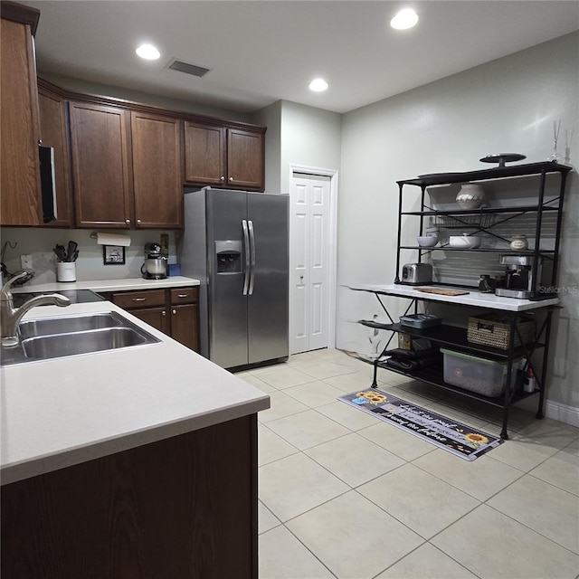 kitchen featuring sink, stainless steel fridge with ice dispenser, dark brown cabinets, and light tile patterned floors