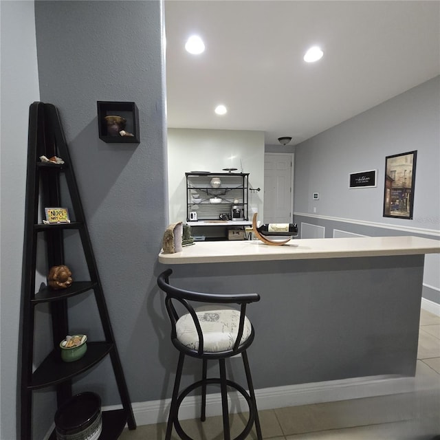 interior space with a kitchen breakfast bar, light tile patterned flooring, and kitchen peninsula