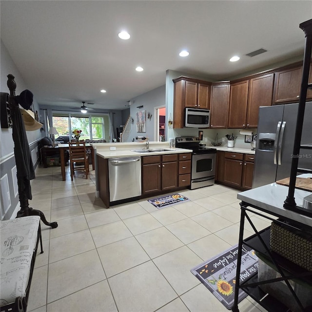 kitchen with appliances with stainless steel finishes, kitchen peninsula, and dark brown cabinetry