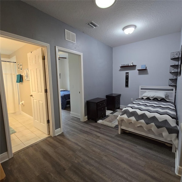 bedroom with a textured ceiling, connected bathroom, and wood-type flooring