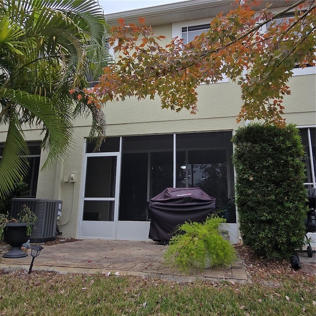 rear view of house featuring a patio area, central AC unit, and a sunroom