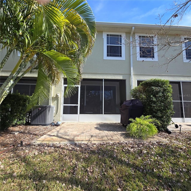 back of house with a sunroom, cooling unit, and a patio area