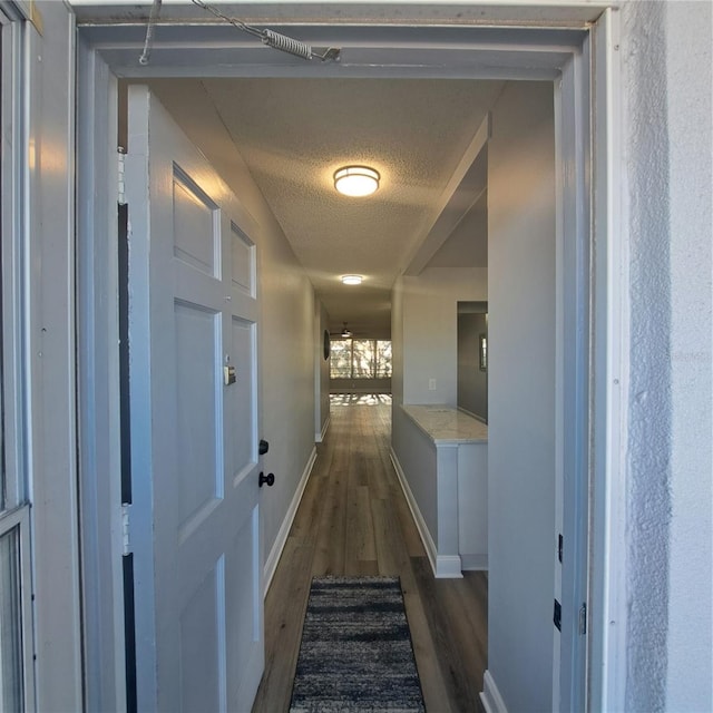 hallway featuring a textured ceiling and dark hardwood / wood-style flooring