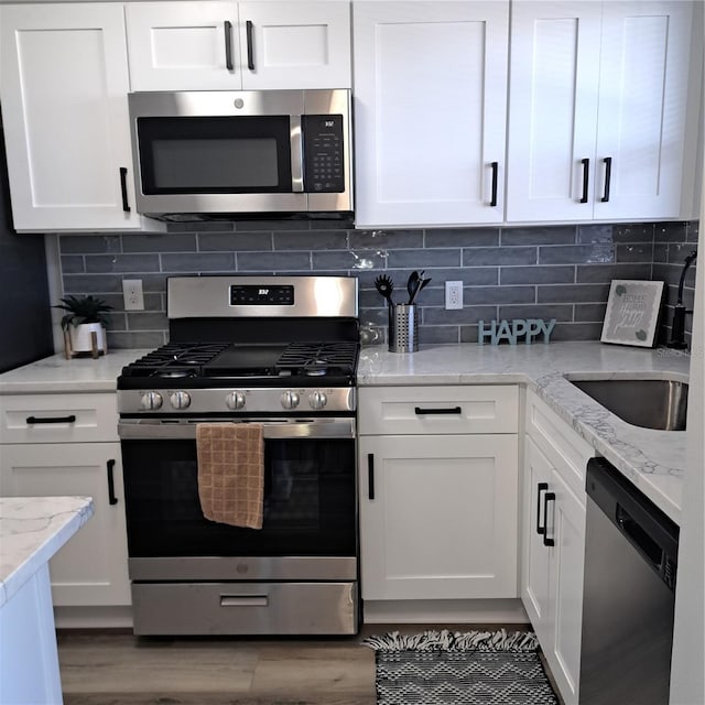 kitchen featuring stainless steel appliances, white cabinetry, and backsplash