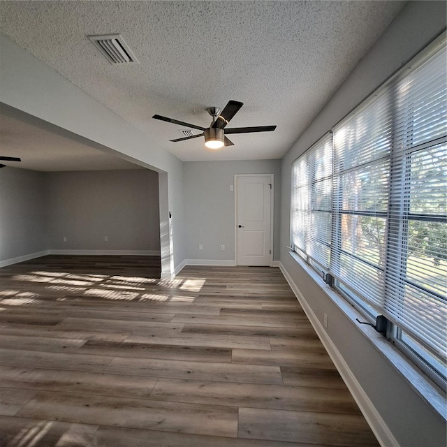 unfurnished room featuring ceiling fan, hardwood / wood-style floors, and a textured ceiling