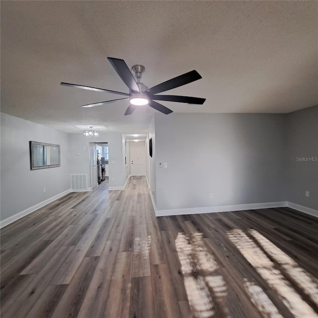 unfurnished living room featuring dark wood-type flooring, a textured ceiling, and ceiling fan