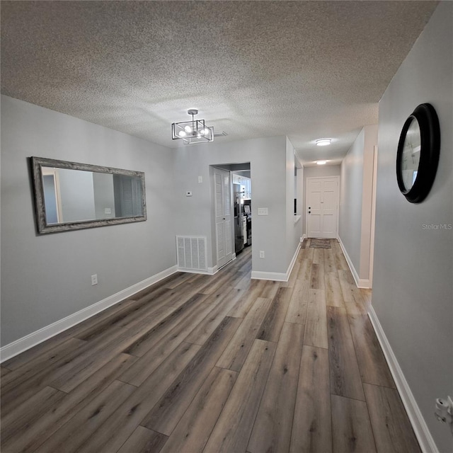 interior space featuring wood-type flooring, a textured ceiling, and a chandelier