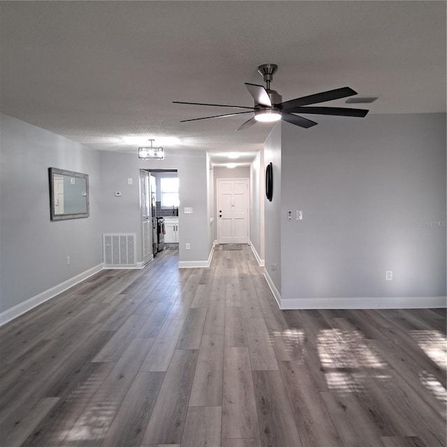 spare room featuring ceiling fan with notable chandelier, a textured ceiling, and hardwood / wood-style floors