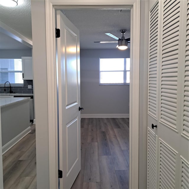 corridor featuring sink, dark hardwood / wood-style flooring, and a textured ceiling