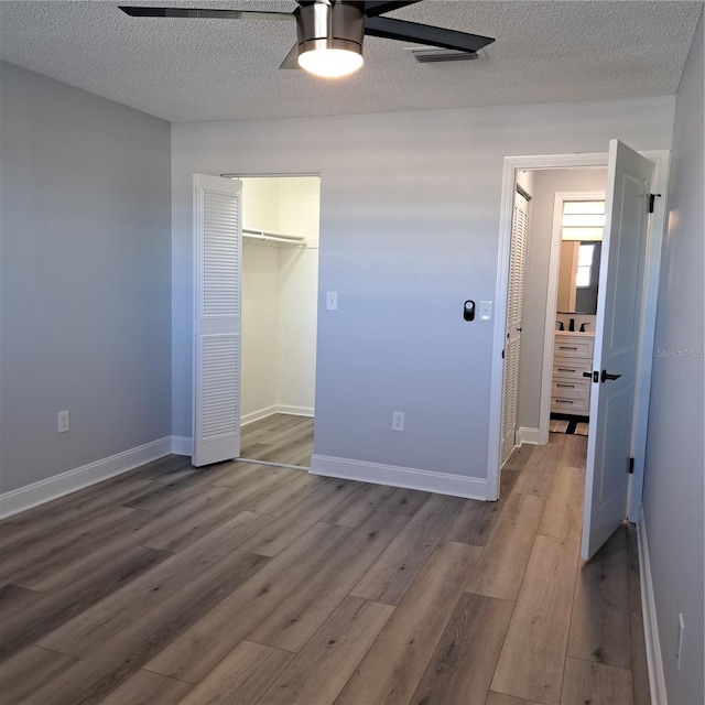 unfurnished bedroom featuring ceiling fan, a closet, a textured ceiling, and wood-type flooring