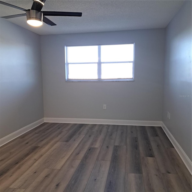 empty room with a healthy amount of sunlight, dark wood-type flooring, a textured ceiling, and ceiling fan