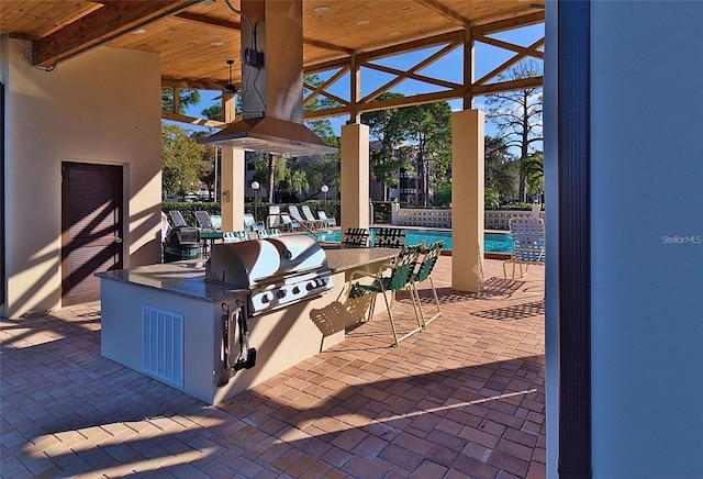 view of patio / terrace featuring exterior kitchen, grilling area, and a community pool