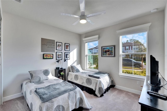 bedroom with ceiling fan, light colored carpet, and multiple windows