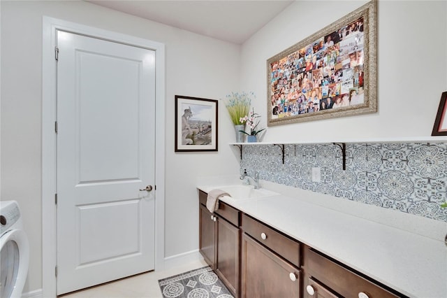 laundry area featuring light tile patterned flooring, cabinets, sink, and washer / clothes dryer