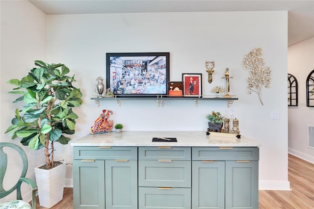 bar featuring light stone countertops and light hardwood / wood-style flooring