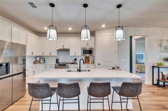 kitchen with a center island with sink, sink, white cabinetry, and stainless steel appliances