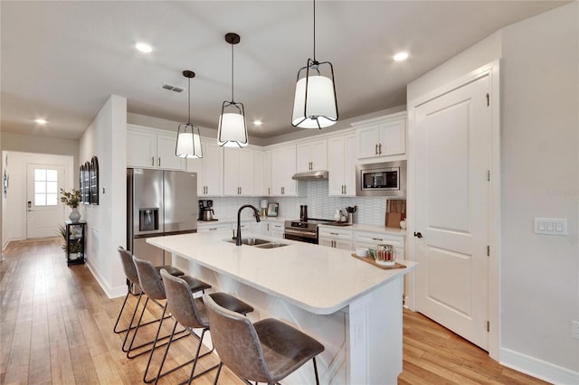 kitchen with white cabinets, an island with sink, stainless steel appliances, and sink