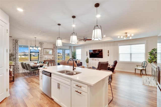 kitchen featuring white cabinetry, dishwasher, sink, a raised ceiling, and a kitchen island with sink